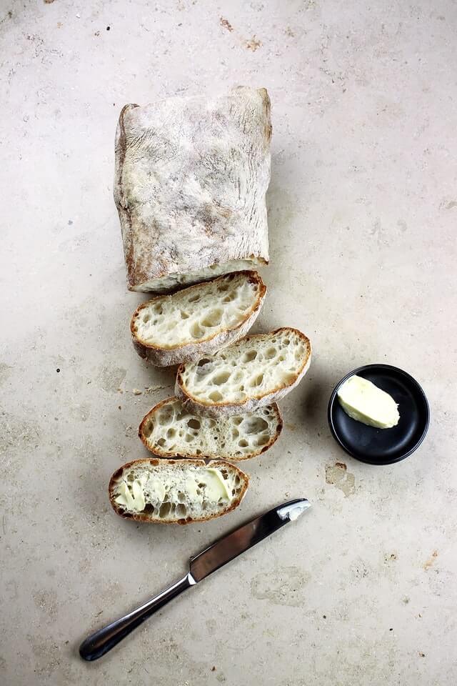 baguette coupée en tranche avec couteau et beurre